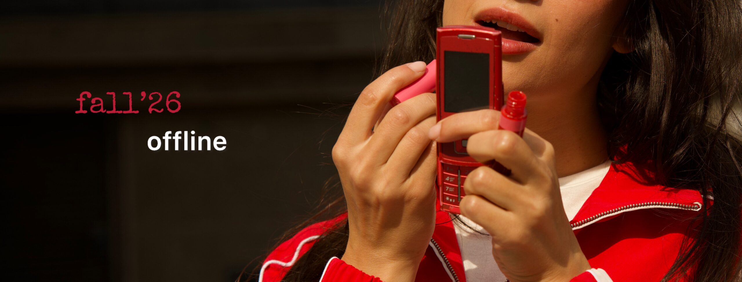 Promotional banner showing a person in a red jacket holding a red flip phone, with 'fall'26 offline' text on a dark background.